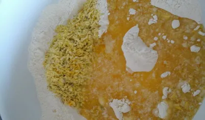 Маргарин растопить и остудить. Муку просеять с разрыхлителем, добавить желток, натёртый на мелкой тёрке, влить маргарин.