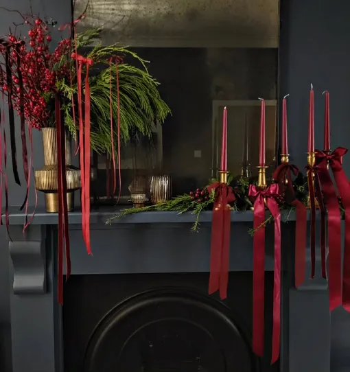 Классические носочки для подарков в качестве украшений не в моде, а вот гирлянды из лапника на каминной полке будут весьма уместны, как и композиции из свечей.