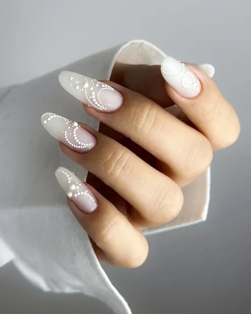 Молочный маникюр с тонкими объемными деталями, напоминающими морозный узор, — стильный и модный дизайн на декабрь 2025 года и Новый год.