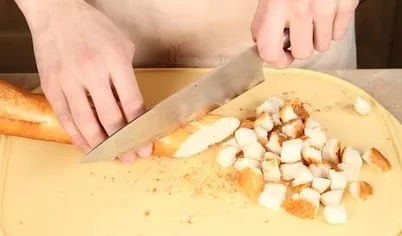 Приготовьте крутоны. Разогрейте духовку до 200°С. Хлеб нарежьте кубиками.