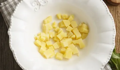 Картофель отварите в мундире. Дайте остыть, очистите, нарежьте мелкими кубиками.