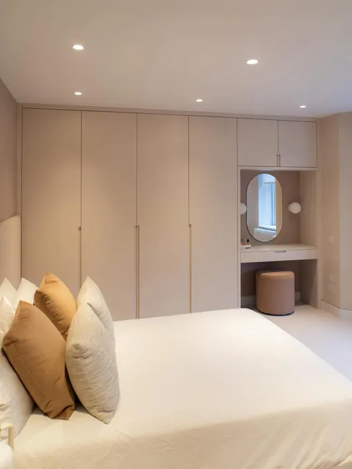 Минималистичный гардероб, имитирующий панели стены, с встроенным туалетным столиком