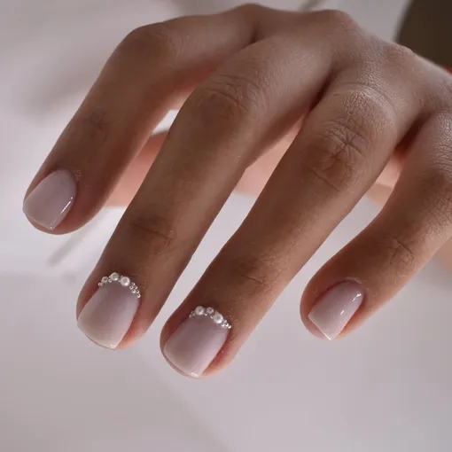 Молочный маникюр, украшенный бусинами-жемчугом, — модный нейл-дизайн любовного маникюра на декабрь 2025 года.