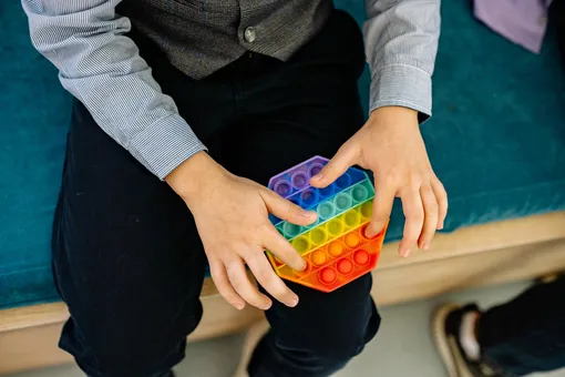 Пальцы подростка играют в поп ит