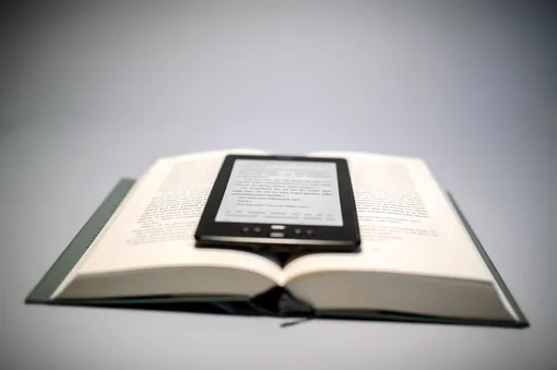 электронная книга лежит поверх раскрытой бумажной электронная книга лежит поверх раскрытой бумажной
