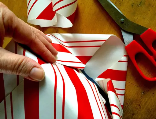 человек упаковывает подарок в бумагу человек упаковывает подарок в бумагу