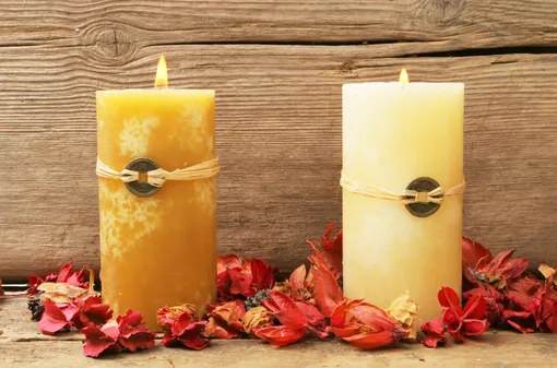 две горящие свечи в лепестках цветов
